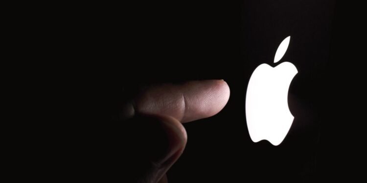 Stone, Staffordshire / United Kingdom - November 13 2019: Finger pointing at glowing Apple logo in a dark. Editorial illustrative photo. Conceptual photo.